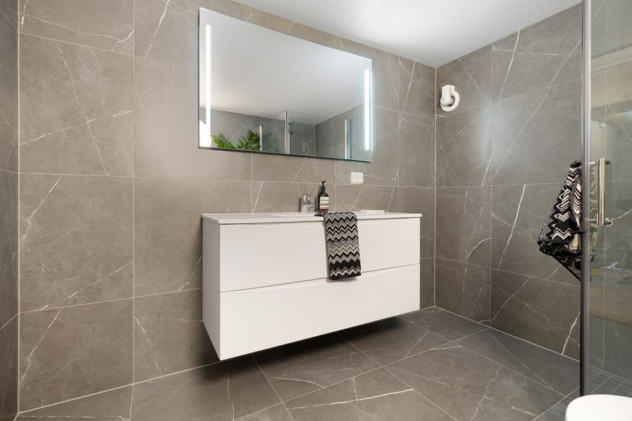Salle de bain moderne en carrelage gris et marbre, avec vasque et miroir